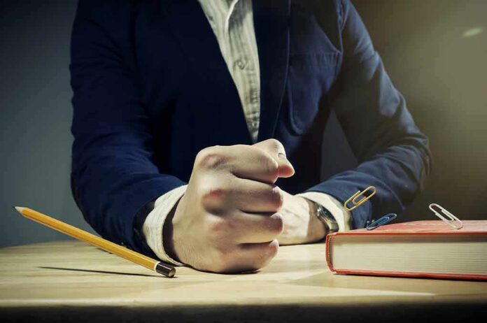 482144998 featured image Person slams fist on desk with pencil and book