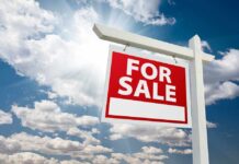 For sale sign against cloudy sky