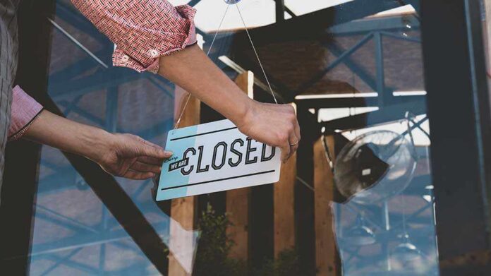 1162554778 featured image Hand placing closed sign on glass door