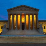 Illuminated building at dusk with columns