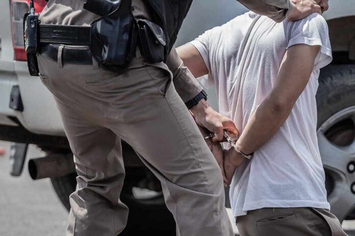 1705187374 featured image Police officer handcuffing person against vehicle wheel