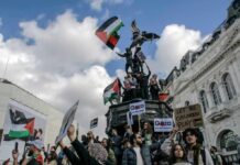 Protesters with flags and signs near a statue