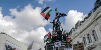 Protesters with flags and signs near a statue