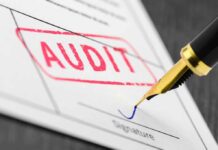 Audit stamp and pen signing a document