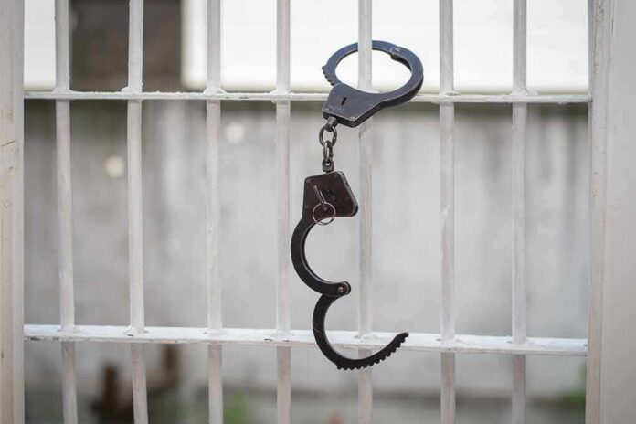 680970664 featured image Open handcuff hanging on white prison bars