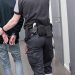 Officer escorting handcuffed person down hallway