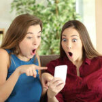 Two women look surprised at a phone
