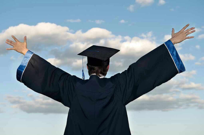 Graduate in cap and gown celebrates under cloudy sky
