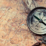 Old compass on a vintage map background