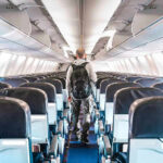 State’s Bold Move: Migrants Choose Their Fate Person walking down empty airplane aisle