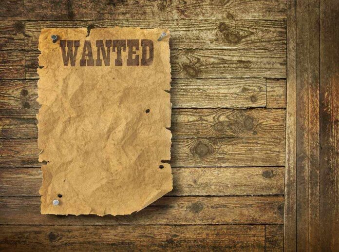A vintage wanted poster pinned to a wooden wall