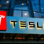 Tesla CRITICAL Flaw Triggers Massive RECALL Tesla logo on a building at night.