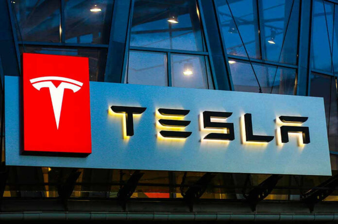 Tesla logo on a building at night.