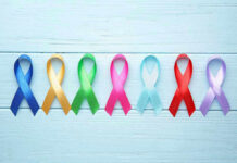 Colorful awareness ribbons on light wooden background.