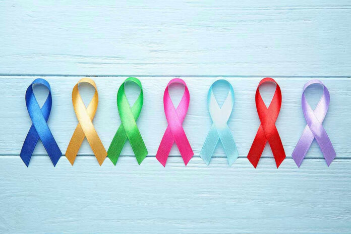 Colorful awareness ribbons on light wooden background.