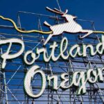 Portland Police CRACKDOWN on Anti-ICE Protests – FINALLY! Neon sign reading Portland Oregon with a leaping deer against a blue sky