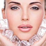 Close-up of a woman holding ice cubes around her face