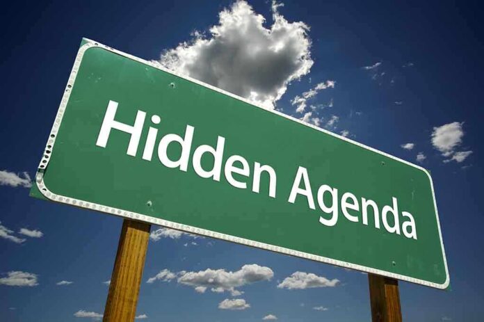 Road sign displaying the phrase Hidden Agenda against a blue sky
