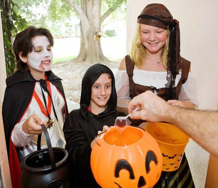 Children in Halloween costumes collecting candy from a house