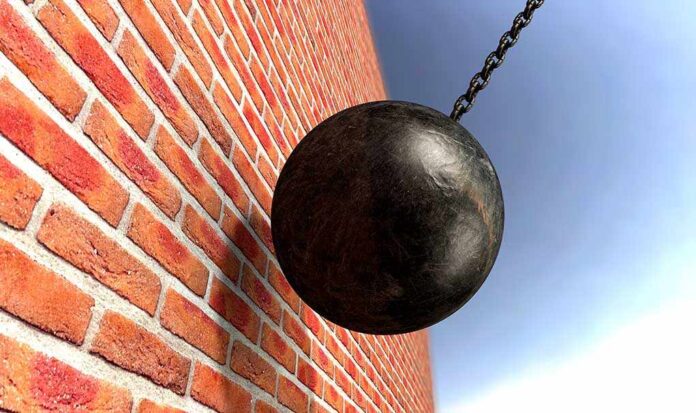 A wrecking ball suspended near a brick wall, suggesting demolition activity