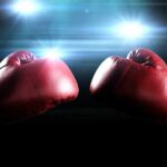 Two red boxing gloves facing each other with dramatic lighting