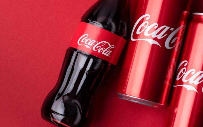 shutterstock_1939168312.jpg Coca-Cola bottle and cans on a red background