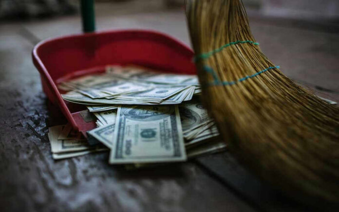 138793661 Broom sweeping dollar bills into red dustpan floor