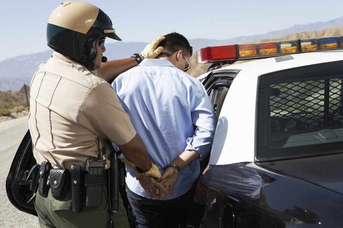 Police officer arresting a suspect near a patrol car