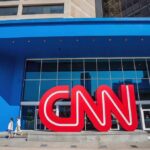 Exterior view of the CNN building with a large red logo and blue facade