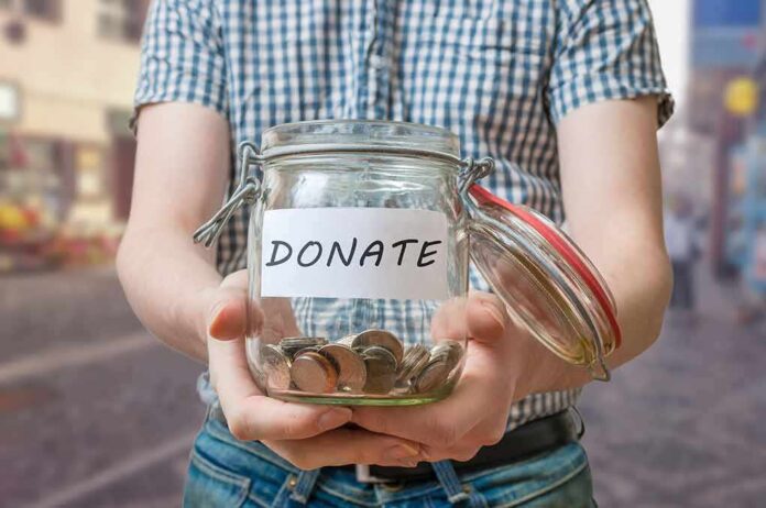 Person holding a glass jar labeled DONATE filled with coins