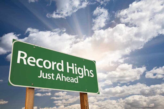 shutterstock_75667870.jpg A green road sign indicating Record Highs Just Ahead against a cloudy sky