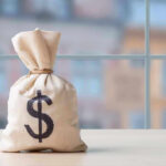 Somali Centers VANISH After Taking Millions Money bag with dollar sign on table.