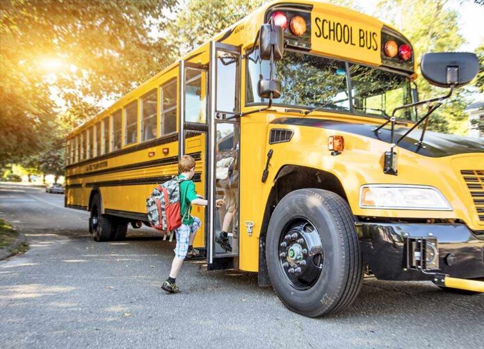 A child with a backpack boarding a yellow school bus