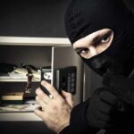 BRAZEN Heist: Pokémon Cards Vanish! A masked burglar holding a gun while attempting to open a safe