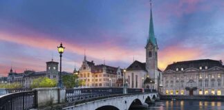 Scenic view of Zurich with a bridge, historic buildings, and a sunset sky