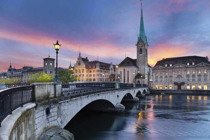 Scenic view of Zurich with a bridge, historic buildings, and a sunset sky