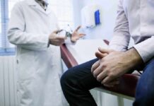 A doctor in a white coat discussing with a patient sitting on an examination table
