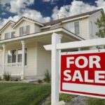 A suburban house with a For Sale sign in the front yard