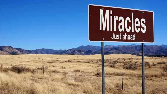 A road sign reading 'Miracles Just ahead' in a desert landscape