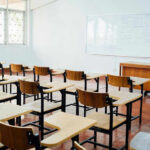 Empty classroom with desks, chairs, and whiteboard.