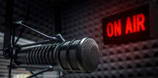 Microphone in soundproof studio with On Air sign.