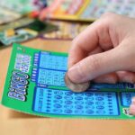 A person scratching off a bingo lottery ticket with a coin
