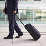 A businessman in a suit walking with a suitcase at an airport