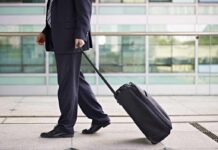 A businessman in a suit walking with a suitcase at an airport