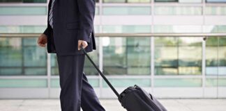 A businessman in a suit walking with a suitcase at an airport