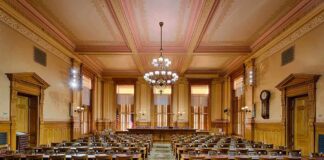 Interior view of a historic courtroom with wooden furnishings and chandeliers