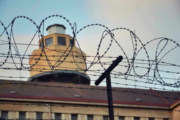 Barbed wire in front of a prison tower.