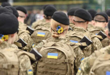 Soldiers in camouflage uniforms with Ukrainian flags.