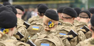 Soldiers in camouflage uniforms with Ukrainian flags.