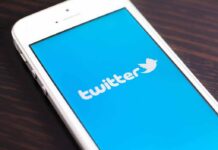 Close-up of a smartphone displaying the Twitter logo on a blue background